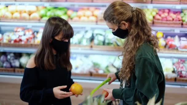 Due donne mascherate che scelgono frutti biologici al supermercato insieme — Video Stock