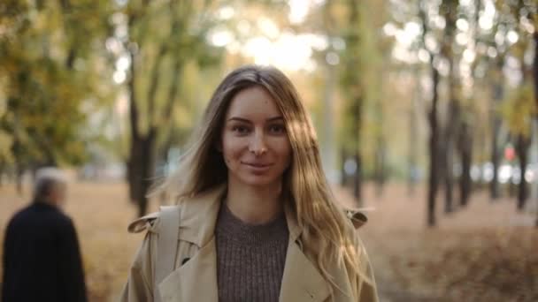 Vue de face d'une femme joyeuse marchant près du parc d'automne — Video