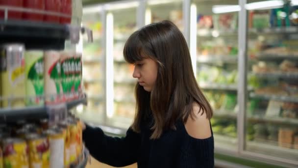 Precioso adolescente en el supermercado, tomando refrescos de la estantería — Vídeos de Stock