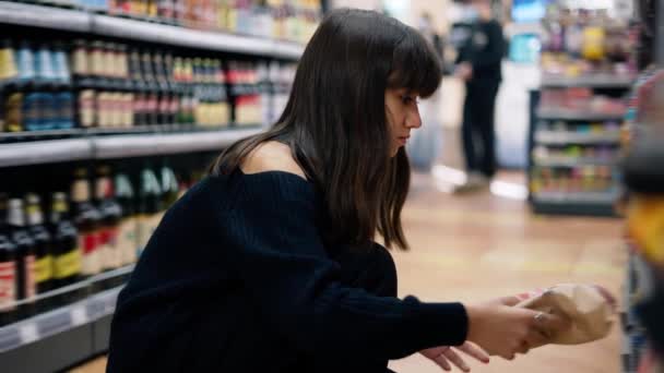 Primer plano de imágenes de una chica en la tienda tomando el producto de la estantería inferior — Vídeos de Stock