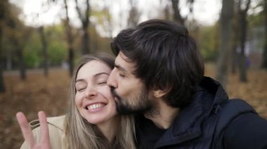 Sonbahar sezonunda parkta bankta selfie çeken sevimli bir çift.