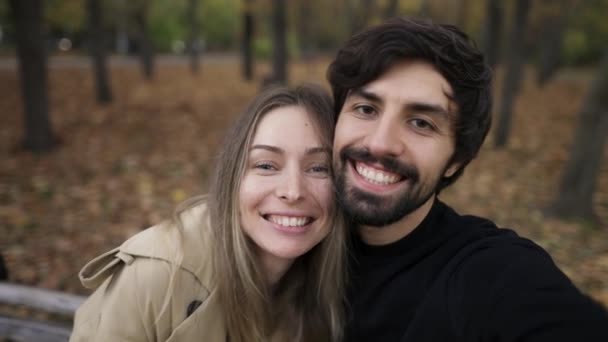 Kærlighed par gør selfie på en bænk i parken i efteråret efterår sæson – Stock-video
