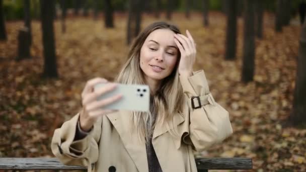 Happy woman sitting on the bench in the park and taking a self portrait — Stock Video