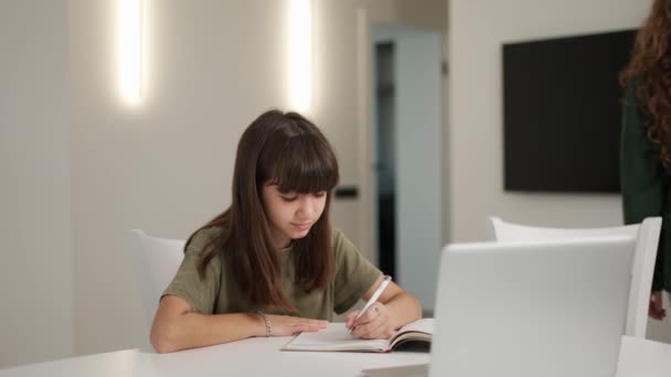 Young mother sits to help her daughter with her homework — Stock Video