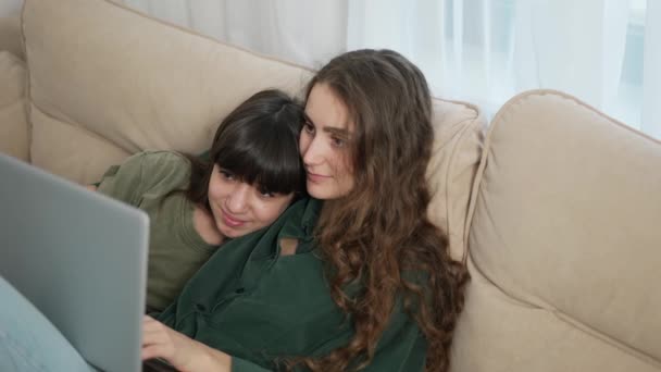 Zwei Mädchen lagen auf der Couch und sahen gemeinsam Film auf Laptop — Stockvideo