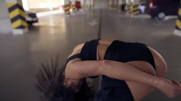 춤을 추는 섹시 한 여자 가 주차장에서 느린 동작으로 현대적 인 역할극을 하는 모습 — 비디오