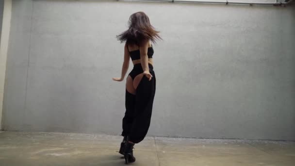 Morena mulher sexy em colinas executa dança moderna, posando contra a parede cinza — Vídeo de Stock
