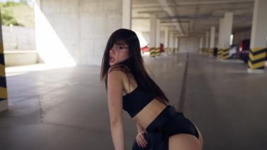 Dans eden seksi kadın modern dans gösterisi yapıyor, poz veriyor, park alanında twerk yapıyor. Kapat.