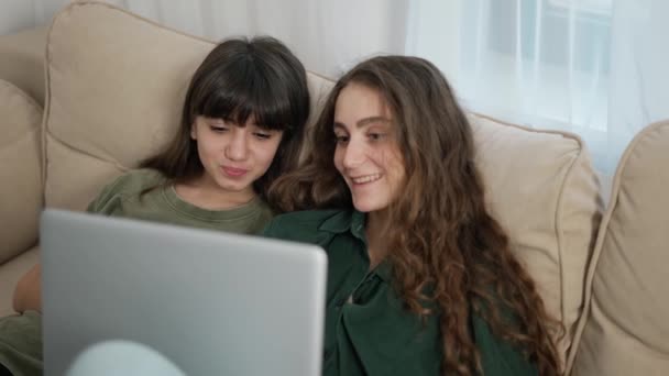 Pár krásných veselých mladých žen s úsměvem při sledování filmu na počítači na pohovce — Stock video