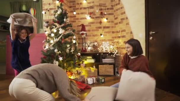 Vidám anya párnacsata boldog kislányokkal a szobában, karácsonyfával díszítve — Stock videók