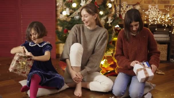 Excited, pretty girls with mom unpacking christmas gifts on the floor — Stock Video