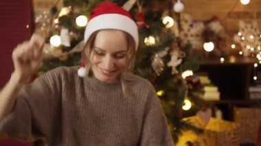 Kırmızı Noel Baba şapkası takan mutlu kız, Bengal parıltılı maytap tutuyor.