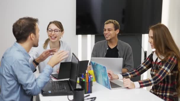 Счастливые творческие деловые люди с ноутбуками в офисе вместе раскручивают проект — стоковое видео