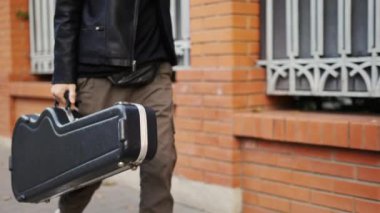 Bir adam sokakta gitar kılıfıyla dolaşıyor.