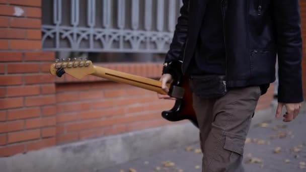 Mann läuft mit Gitarre über die Straße — Stockvideo