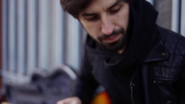 Giutar 'da bir adam dışarıda penayla oynuyor.