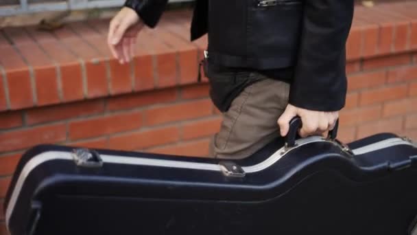 Hombre caminando por la calle con un estuche de guitarra — Vídeo de stock