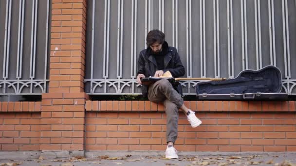 Mannen tar hand om gitarren som sitter på gatan — Stockvideo