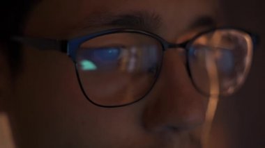 Geceleri ticaret yapan adam monitöre bakıyor, gözlüklerdeki yansımalar...