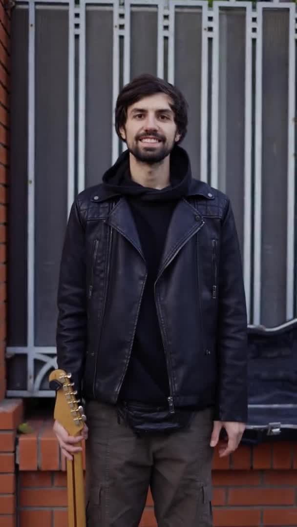 Hombre sonriendo en la calle y llevando una guitarra — Vídeo de stock
