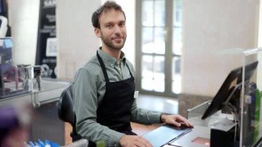 Süpermarkette yakışıklı bir adam bir sonraki müşteriyi bekliyor. Gülümseyen kasiyer