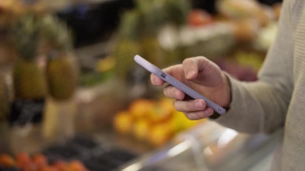 Close-up van een man met behulp van mobiele smartphone in de supermarkt — Stockvideo