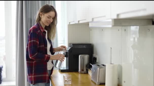 女人往杯子里倒水，在厨房里喝水 — 图库视频影像