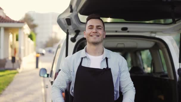 Friendly smiling man with braces holding wooden box with apples at street outdoors, portrait of happy deliveryman in apron and gloves. Online shopping delivering, smart vegetables express delivery — Vídeos de Stock