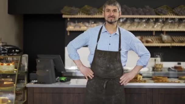 Friendly Male baker wipes his hands on an apron from flour and puts hands on hips — Αρχείο Βίντεο