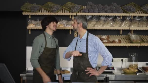 Close up portrait of happy father and son, family business owners, high five in their bakery store, looking at camera and smiling — Wideo stockowe