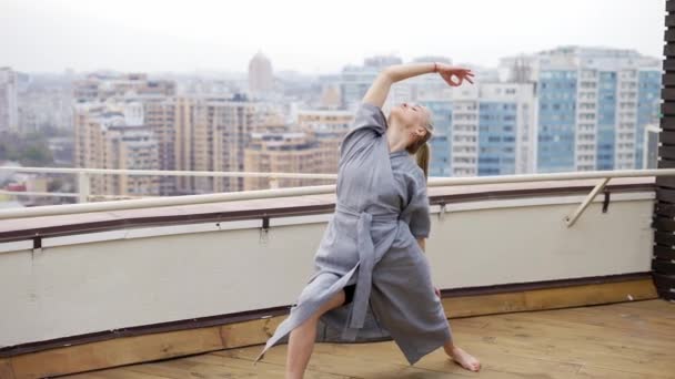 Elegant woman in stylish blue robe practicing yoga at terrace — Vídeo de Stock