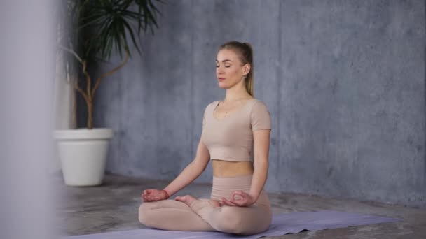 Attractive caucasian woman sitting in lotus pose or Padmasana with closed eyes, holding her hands in Gyan Mudra — Stockvideo