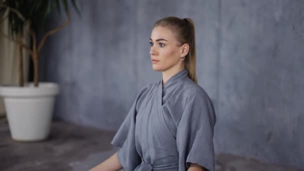 Elegant woman in stylish robe sitting in lotus pose — Stockvideo