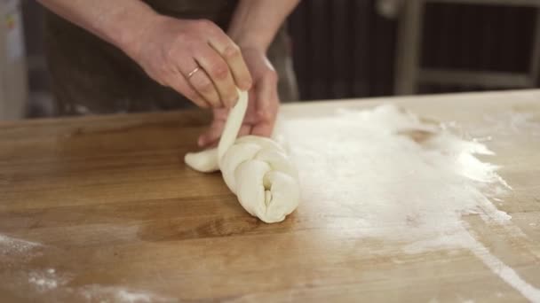 Baker kneads dough and making bread. Chef weaves a pigtail from dough on table. Baker hands close up. Preparing bread. Male hands close-up — Vídeo de Stock