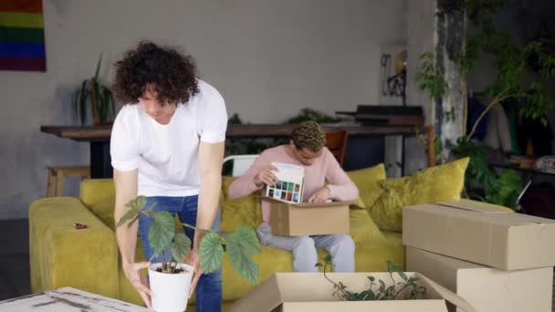 Гомосексуальна пара переїжджає в нову квартиру, розпаковуючи коробки — стокове відео