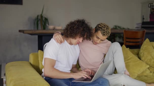 Två manliga homosexuella par omfamnas med hjälp av bärbar dator surfa internet tillsammans för skojs skull — Stockvideo