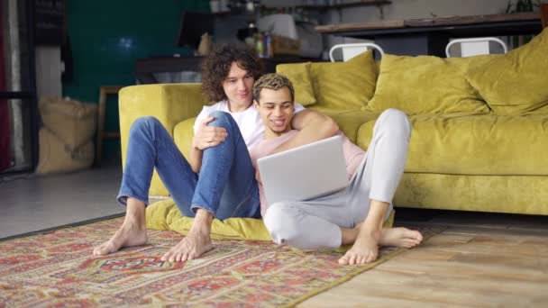 Homme romantique gay couple assis sur le sol ensemble, regardant sur ordinateur portable écran — Video
