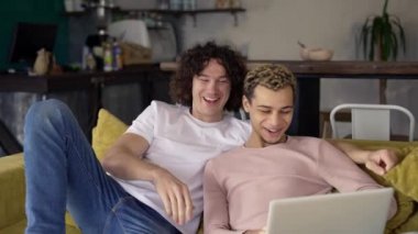 İki erkek eşcinsel çift, interneti görüntülemek veya sörf yapmak için dizüstü bilgisayar kullanıyor.