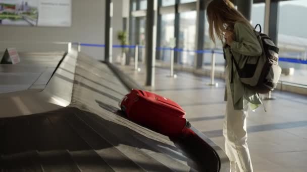 Mujer viajera esperando en el aeropuerto junto al equipaje, revise el estuche en las cintas transportadoras — Vídeos de Stock