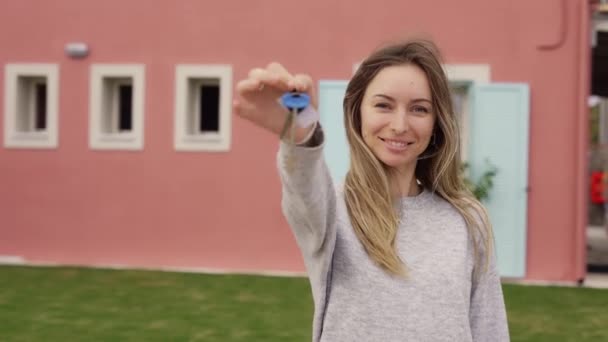 Tevreden dame toont sleutels van nieuw appartement buiten nieuw huis — Stockvideo