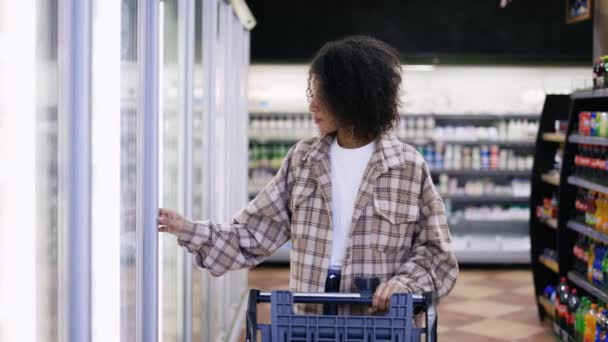 Mujer de compras con carro, abrir la puerta de la nevera en el supermercado — Vídeos de Stock