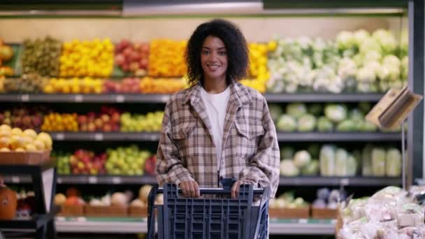 Schöne schwarze Frau mit Einkaufswagen im Supermarkt — Stockvideo
