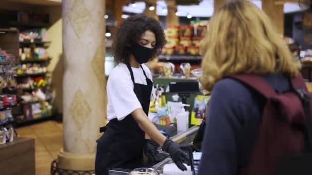 Portrait of female worker at grocery store checkout with client — Stock Video