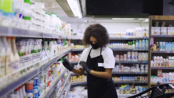 Arbeiterin sortiert Produkte in den Regalen der Milchabteilung eines Lebensmittelgeschäfts — Stockvideo