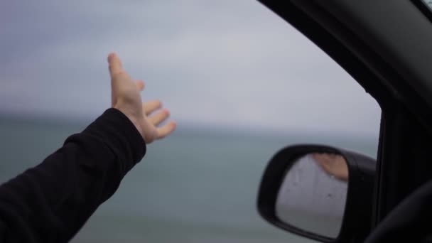 비오는 날 차를 운전하다가 한 사람 이손으로 빗물을 잡고 있는 모습 — 비디오