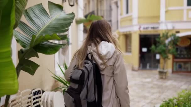 Egy nő sétál a város utcáján hátizsákkal, egy turista megnézi a város látnivalóit. — Stock videók
