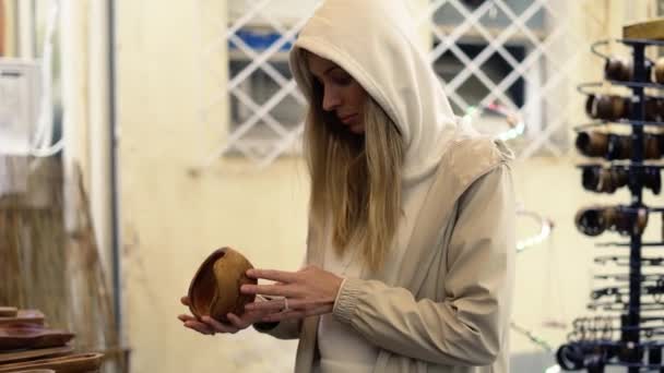 Femme touristique dans le shopping de capuche au bazar de la rue de la ville, à la recherche d'objets artisanaux en bois — Video