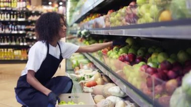 Kıvırcık dişiler büyük yeşil elmaları yavaş çekimde rafa koyuyorlar.