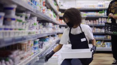 Süpermarketteki süt reyonunda ürünleri düzenleyen kadın işçi, yavaş çekim