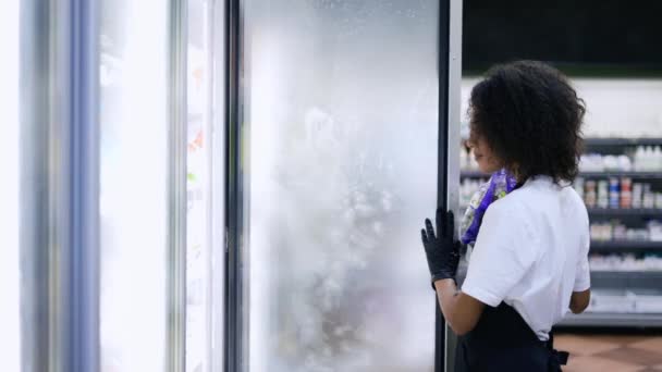 スーパーマーケットの労働者の肖像食品と冷凍庫を開く製品を補充する — ストック動画